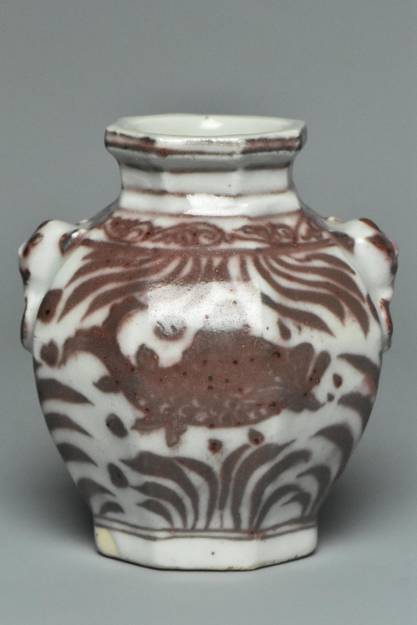 AN UNDERGLAZED RED JAR WITH MASK HANDLES: AN UNDERGLAZED RED JAR WITH MASK HANDLES. Dimensions: 3 3/4 x 3 x 2 3/4 in. Provenance: Formerly in the collection of the Marshall Coyne, noted Washington, D.C. Hotelier, friend of statesmen, etc.. He