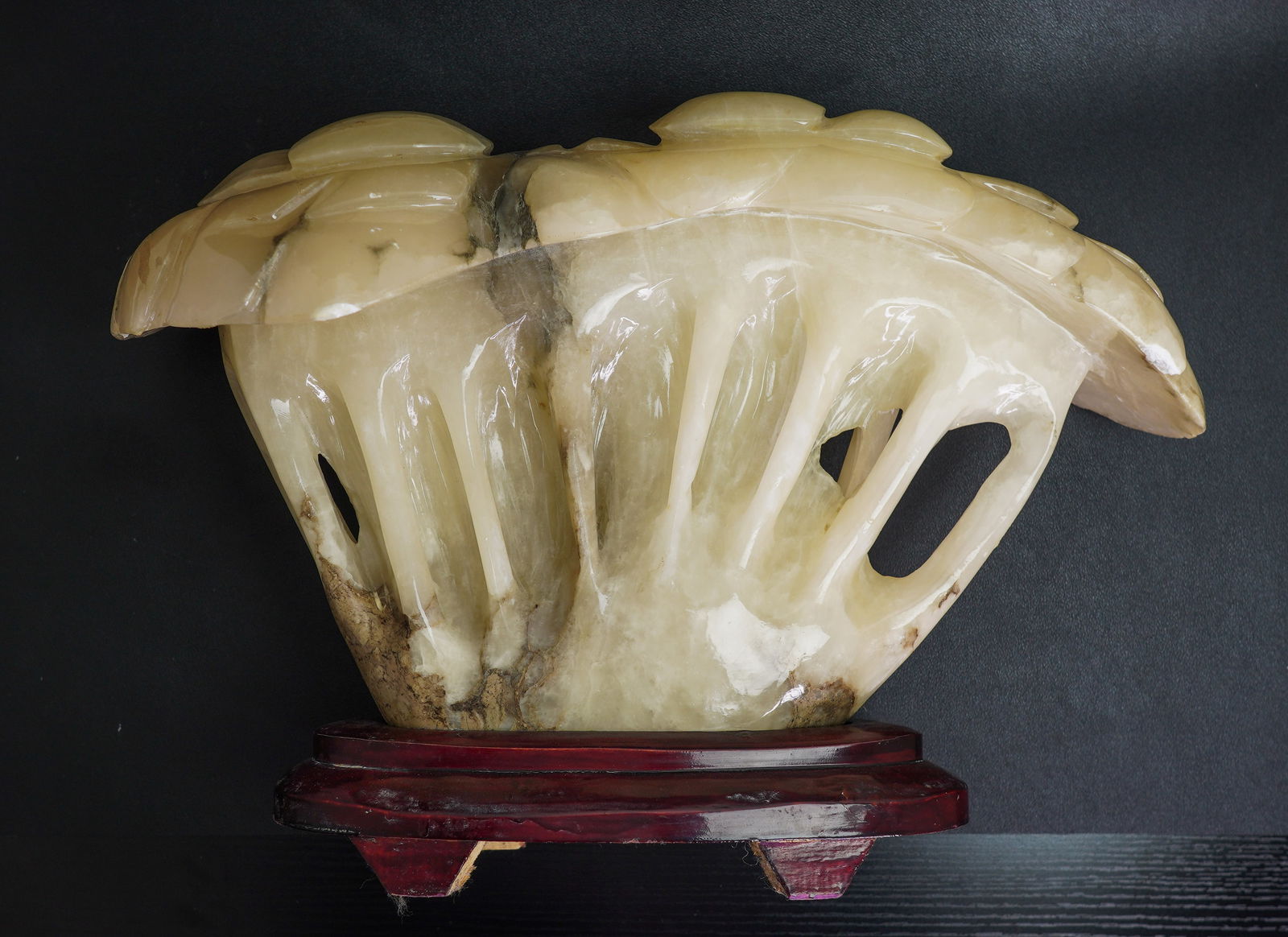 A white stone mushroom sculpture, China, 20th century: Size: 18" x 7" x 14". Weight: 24 lbs (10.6 kg). Description: On a red lacquered wooden base. Natural inclusions and feathering to the stone. Chips. Minor wear and stains. Over weight, tri-State area i