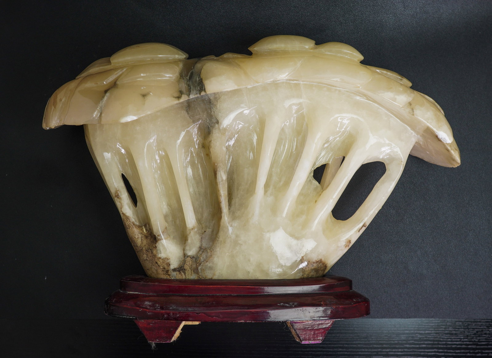 A white stone mushroom sculpture, China, 20th century: Size: 18" x 7" x 14". Weight: 24 lbs (10.6 kg). Description: On a red lacquered wooden base. Natural inclusions and feathering to the stone. Chips. Minor wear and stains. Over weight, tri-State area