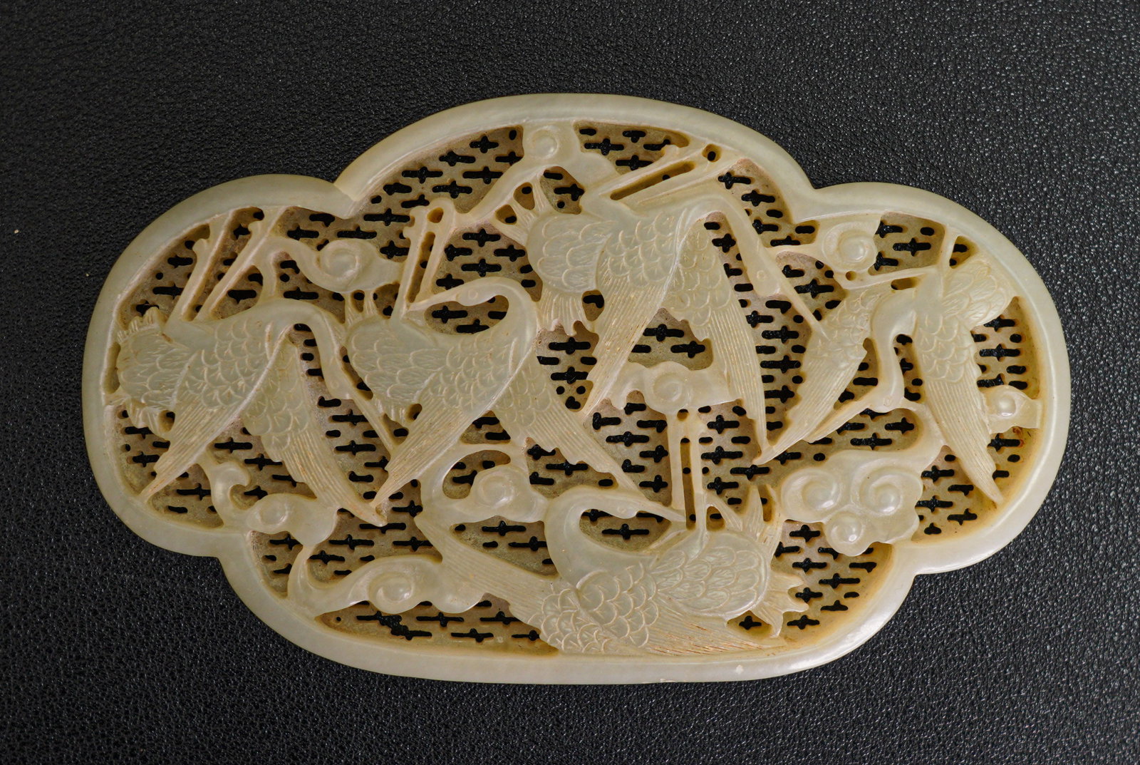 A CHINESE WHITE JADE CARVED OPENWORK PLAQUE OF CRANES, QING DYNASTY (1644-1911): Size:5" x 3" x 1/4". Weight: 4 oz. Description: The quatrelobed plaque carved with a quintet of cranes taking flight amidst swirling clouds and set against a reticulated ground. Tri-State area in hous