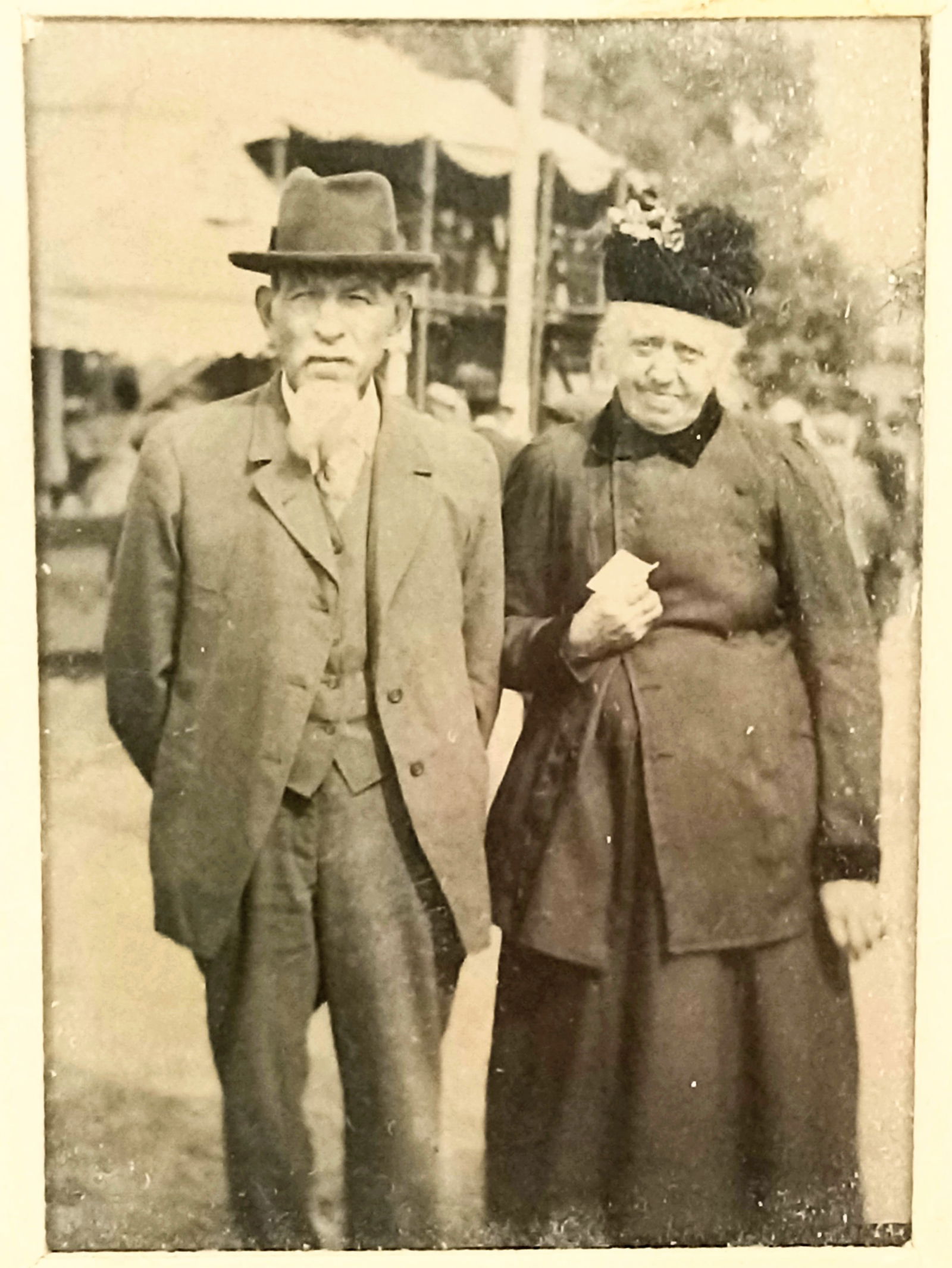 Tintype Photo Interesting Couple Fair: Tintype Photo Interesting Couple Fair? Background possibly looks like carnival tents and people in background, anything possible.Size 2" x 2 1/2" with border 3" x 3 1/2"