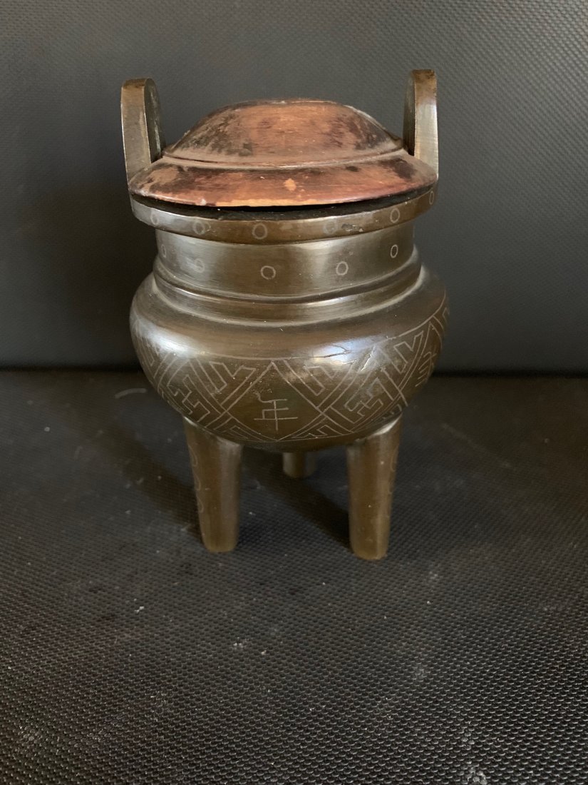 Small Bronze Ding, Qing Dynasty: Small Bronze scholar's Ding in archaistic style with incised decoration of "Wan" and calligraphy surrounding the body. Ancient calligraphy on base. Still retains the damaged lid, but the base has been