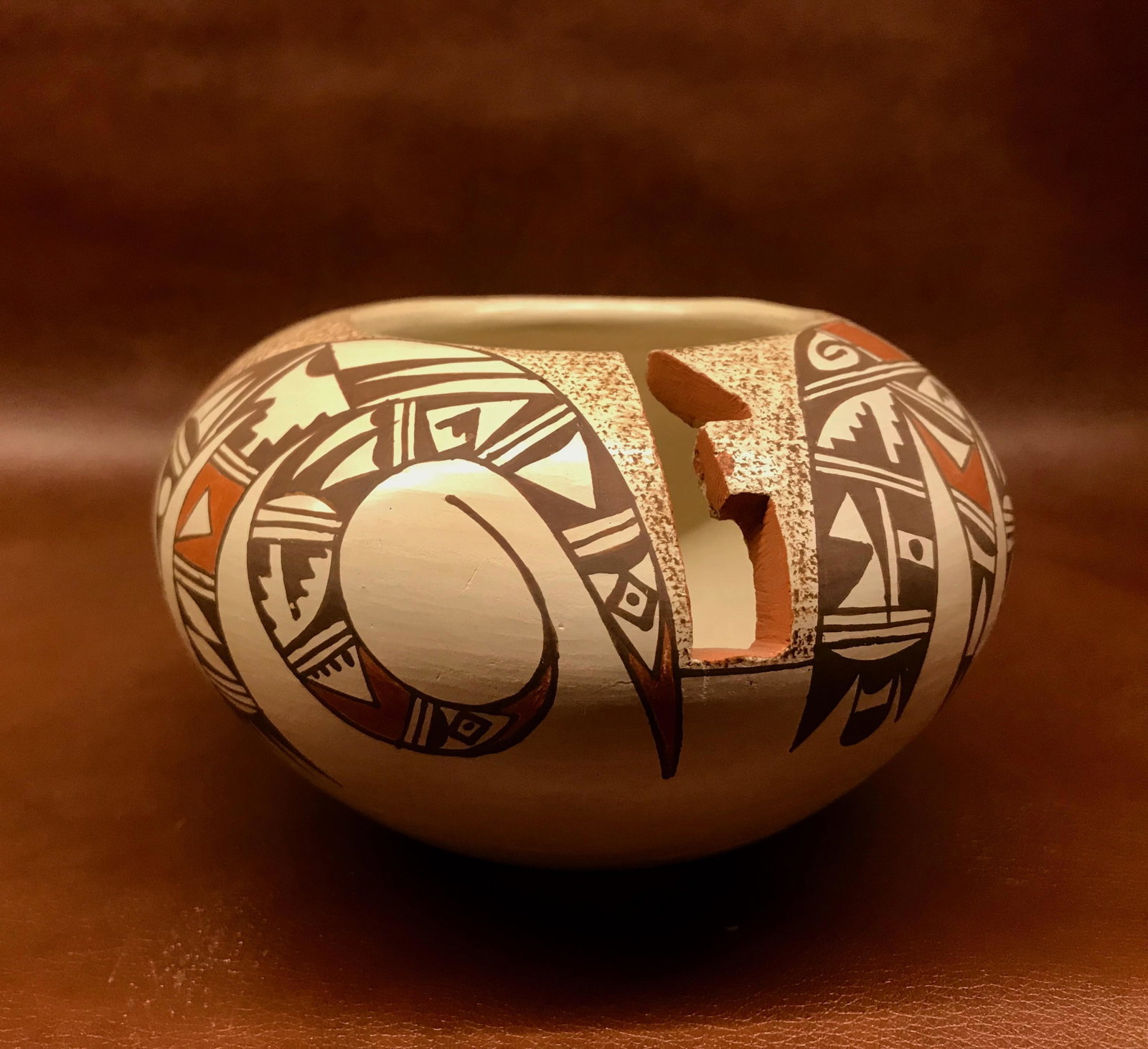 Irma David: Neutral ground with stylized birds painted in red and brown pigments. A 1.5"" geometric cut-out is on the side of the pot. Signed ""I. David"" on base. Good condition. 3.5""H x 4.75""diameter.