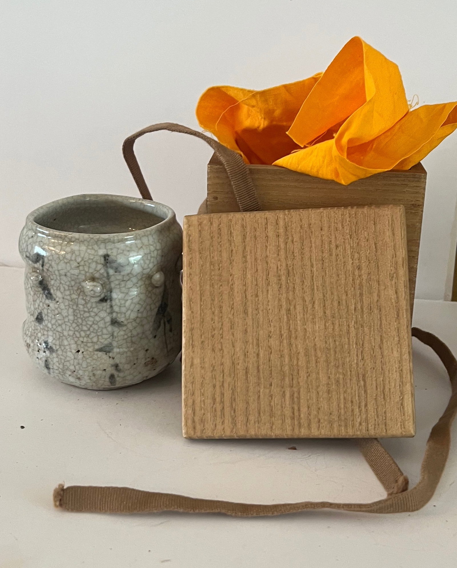 Japanese Stoneware Tea Bowl, Momoyama Period: Deep tea bowl with tall walls, applied decorative bosses, covered in a crackle white glaze and decorated with trees in iron oxide. Comes with wooden box. Late Momoyama/Earlly Edo Period Provenance: Mo