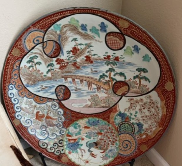 A Colossal Japanese Imari Porcelain 'Peacock and Landscape' Charger: A massive porcelain charger of impressive proportions, richly decorated in the Kinrande style with underglaze blue, iron-red enamels, and highlights of gilding. The interior is divided into dynamic, o