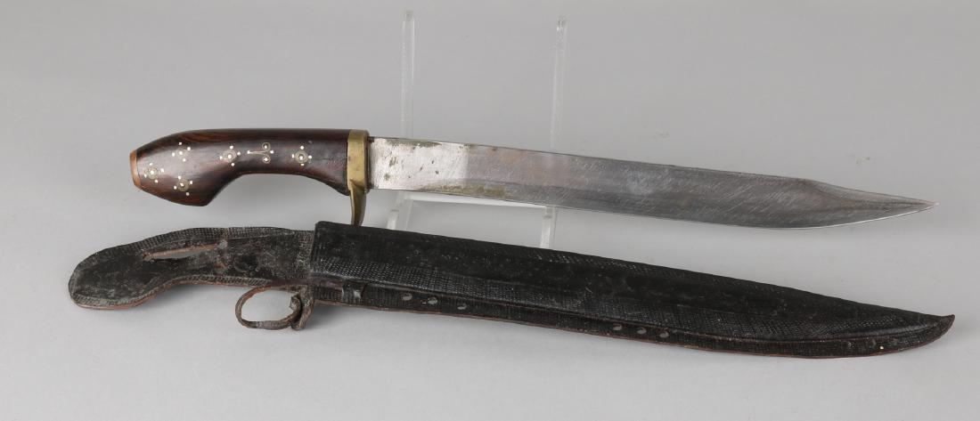 Old Oriental dagger with leather crafted scabbard and tropical wooden handle wit: Old Oriental dagger with leather crafted scabbard and tropical wooden handle with silver and copper inlays. 20th century. Size: 41 cm. In good condition.