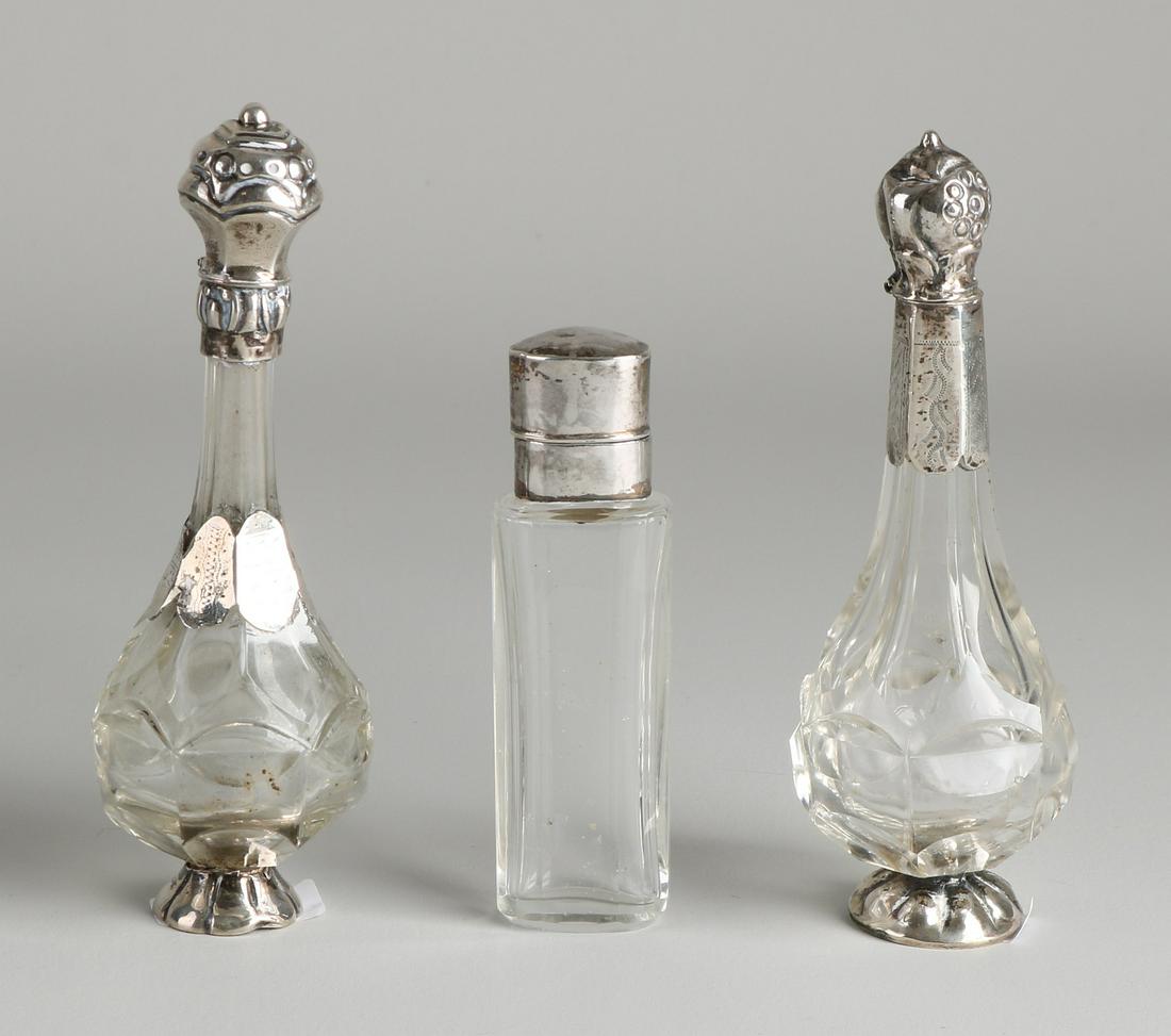 Three perfume bottles with silver. 2 Belly flasks: Three perfume bottles with silver. 2 Belly flasks on a silver base with a silver collar and cap, fitted with an assembled treatment. And a cylindrical bottle with a silver cap and collar, fi