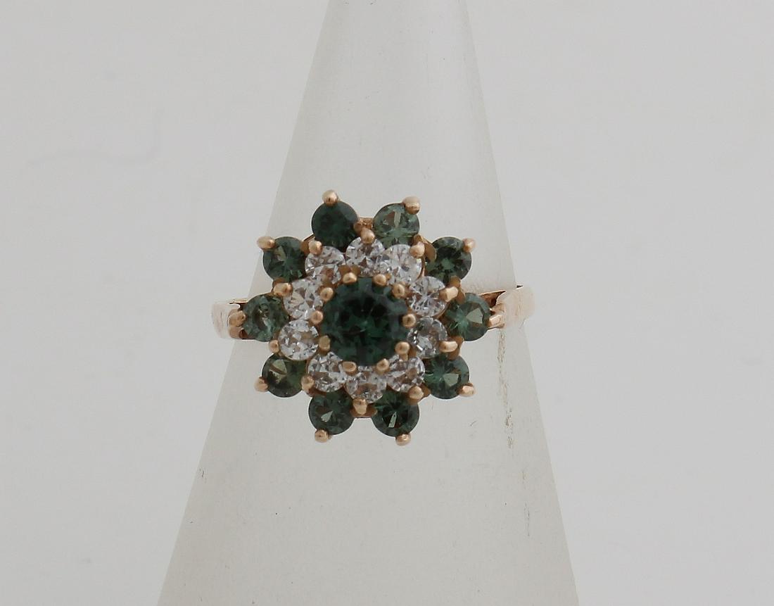 Rosette ring, 375/000, with zirconia's. Ring with: Rosette ring, 375/000, with zirconia's. Ring with a rosette in the middle, set with a greenish stone, surrounded by a border with 10 zirconias and a border with 10 greenish stones. ø he