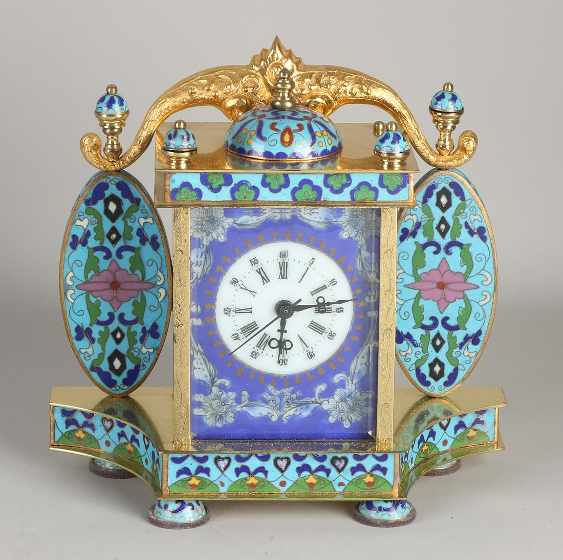Large cloisonne brass gilded table clock with floral: Large cloisonne brass gilded table clock with floral decoration + enamel portrait plaques on the sides. Mechanical, eight-day, with central second hand. Size: 22 x 22 x 9 cm. In good condition.