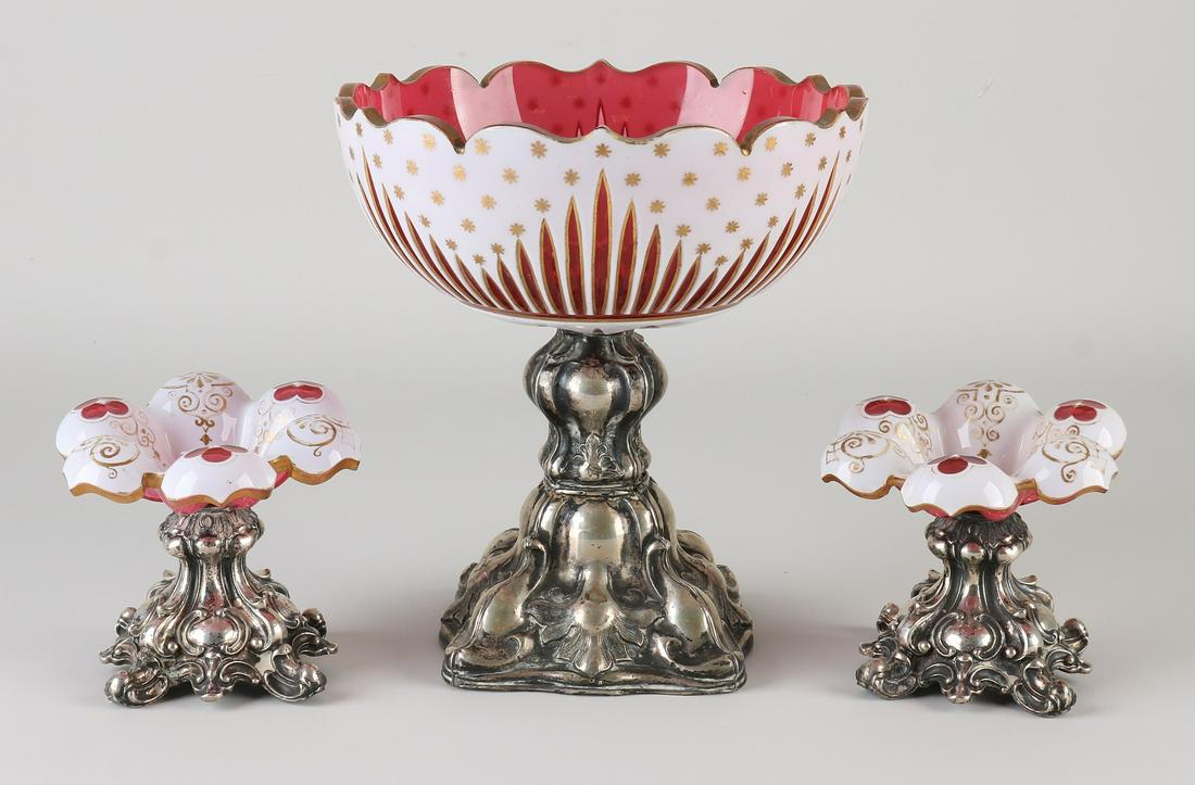 Table set with Bohemian glass and silver, 800/000,: Table set with Bohemian glass and silver, 800/000, 3-piece, with a round bowl of Bohemian glass with red white and gold decor, placed on a square contoured silver base with lobes and acanthus leaves. 