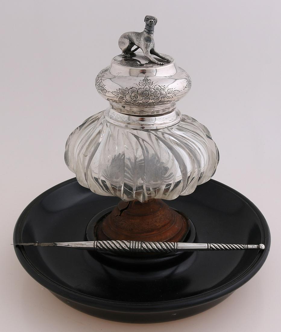 Inkwell and pen with silver: Crystal inkwell on copper base with round black wooden base fitted with a silver collar and cap, 833/000, decorated with floral engraving and crowned with a reclining dog. MT.: Unclear, Amsterdam, jl.