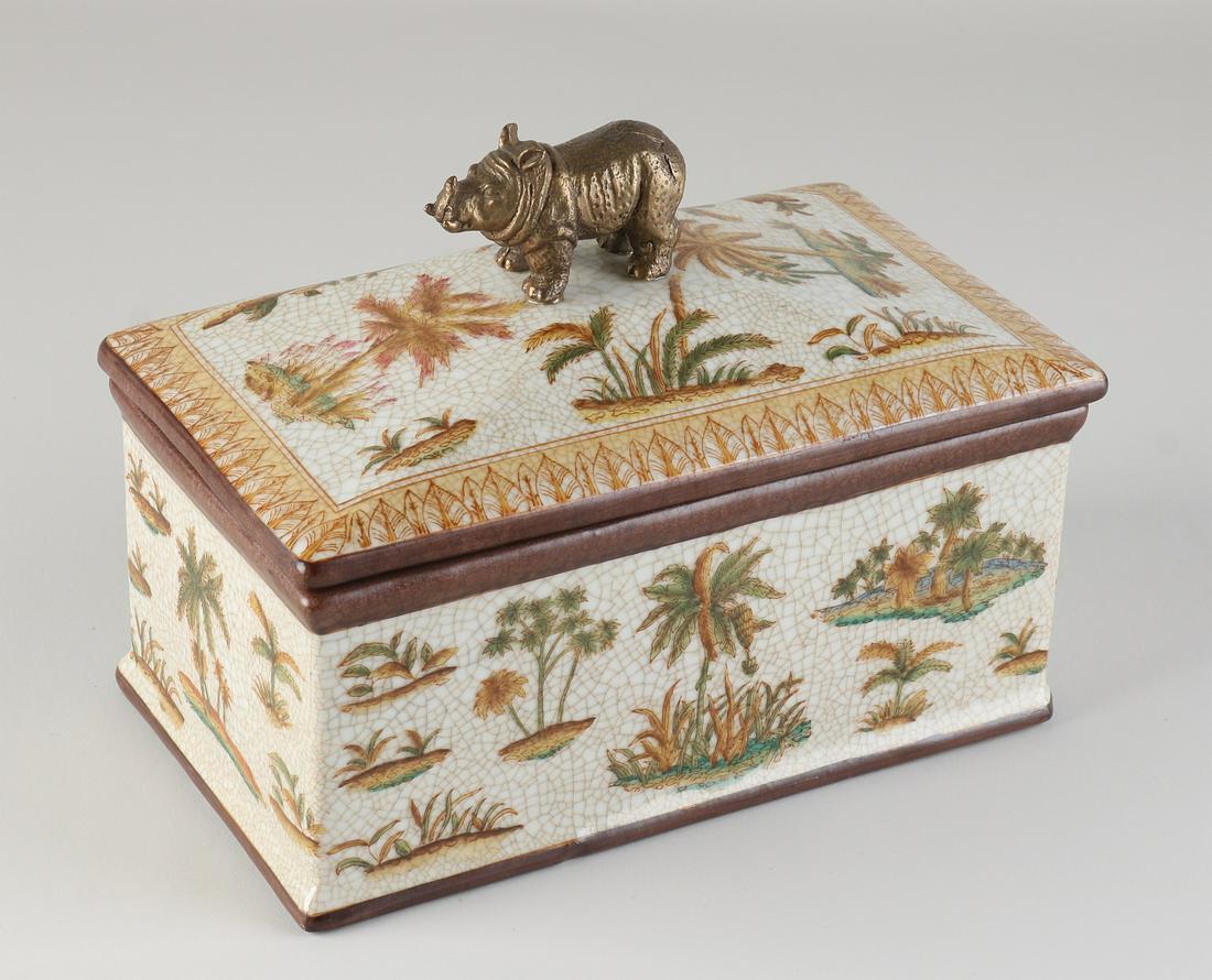Porcelain lidded box: Large porcelain elongated lidded box with tropical decor and bronze rhinoceros. 21st century. Dimensions: 16 x 21 x 12 cm. In good condition.
