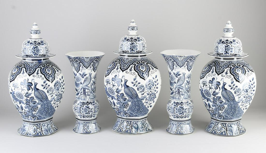 Delft cabinet set, 1900: Antique Dutch Delft fayence garniture. Circa 1900. Societe Ceramique Maastricht. Floral/peacock decor. One hairline. Minimal chip possible. Dimensions: H 26 - 36 cm. In good condition.