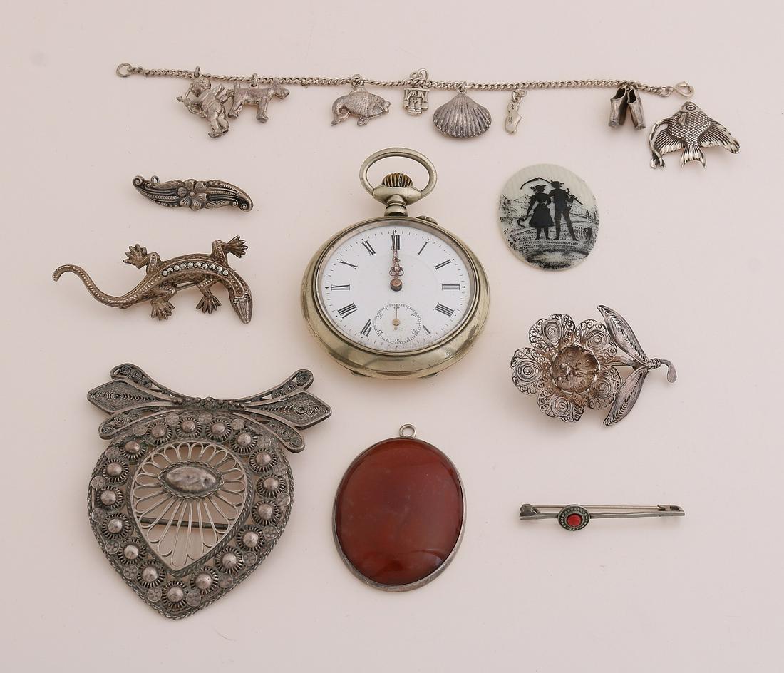 Lot of jewelry: Lot of jewelry with silver charm bracelet with 7 charms, a silver pendant with agate, charm fish, silver lizard and flower brooch. A pocket watch, part filigree clasp, and 2 brooches.