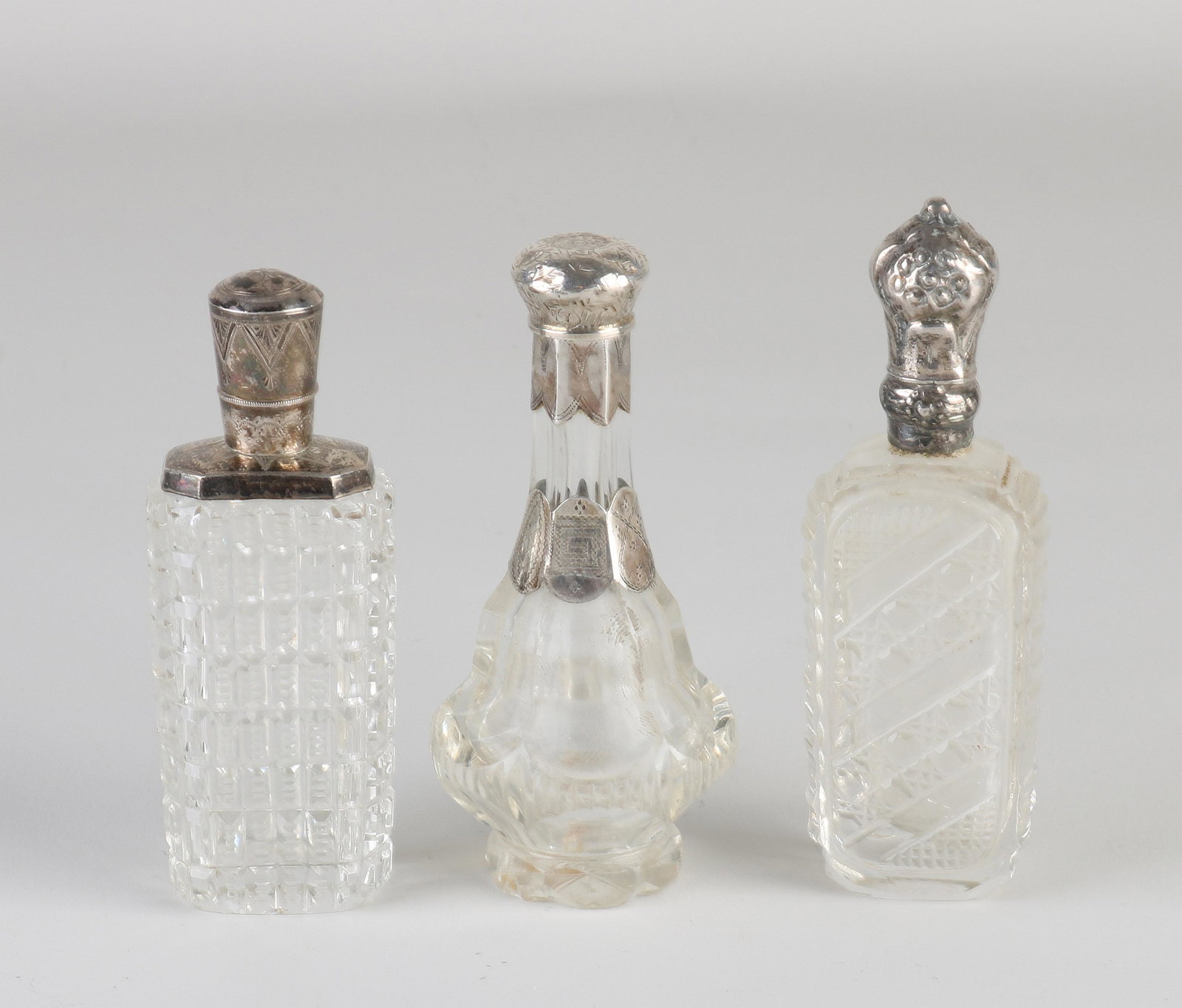 Three perfume bottles with silver: Three odeur flasks, crystal with silver, 833/000, a rectangular flask with cube cut, fitted with a