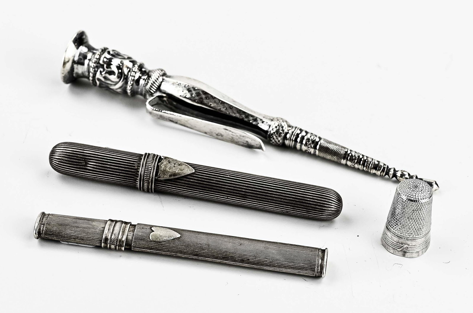 Four parts silver sewing accessories: Four volumes of silver sewing accessories, 833/000, with 2 needle cases, one round and one oval with rib decor and shield, and one filled with a silver darning needle. a thimble and a knitting sheath