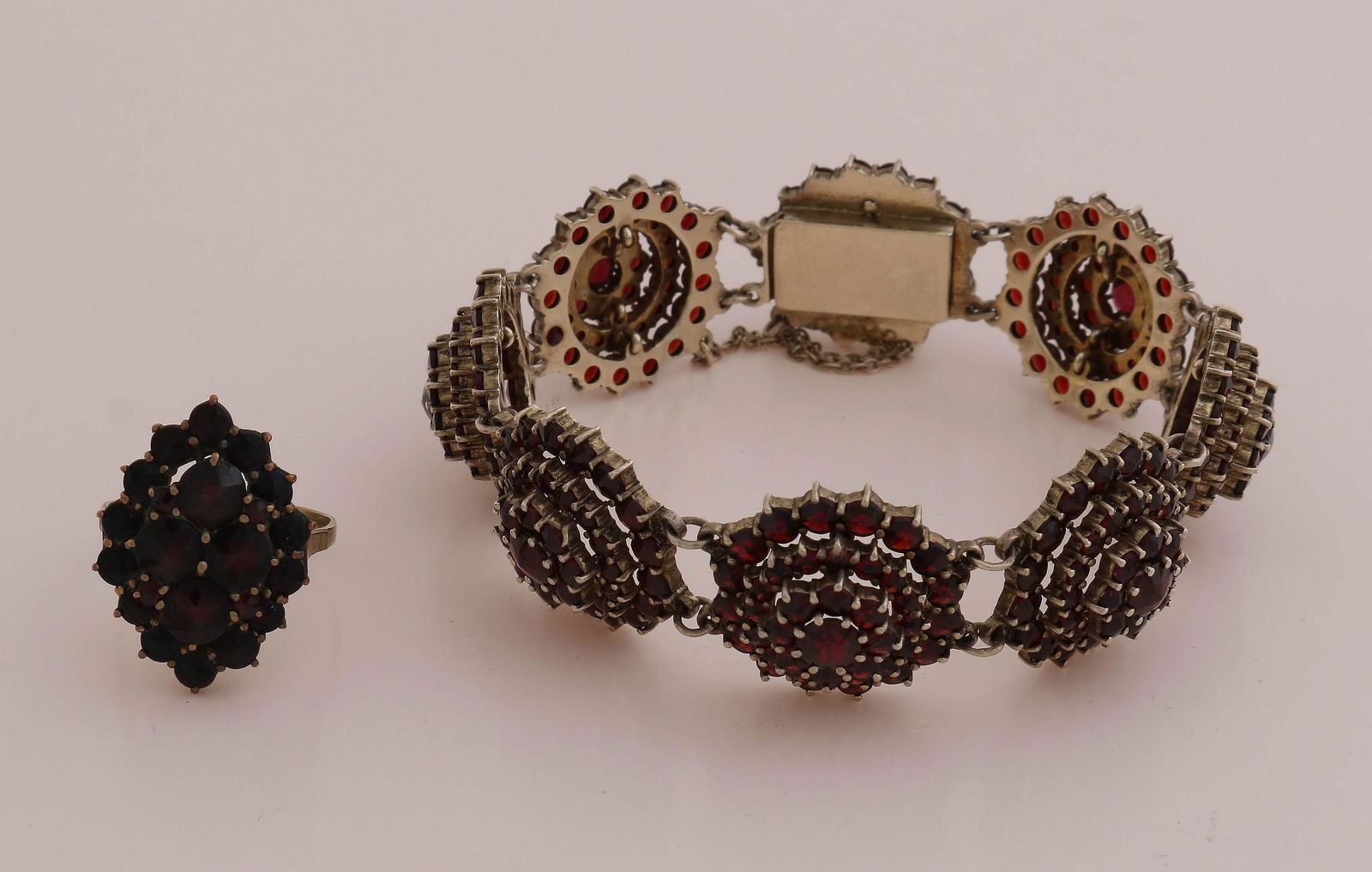 Garnet Bracelet & Ring: Bracelet and ring, gold plated, set with garnet stones. Bracelet with 8 round links with a rosette with garnet stones. The bracelet has a box lock and safety. Width 24mm. Length 19.5 cm. And a ring wi