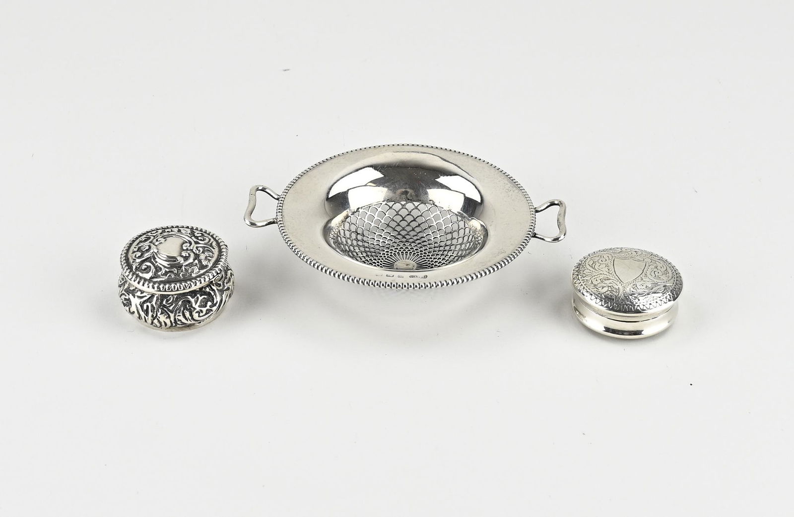 Three parts silver: Three parts silver, 925/000, with a tea strainer, round model with a pearl rim and handles, 10x8cm, MT.:Gorham Manufacturing Co, Birmingham, and 2 pill boxes, round models, one with embossed floral de