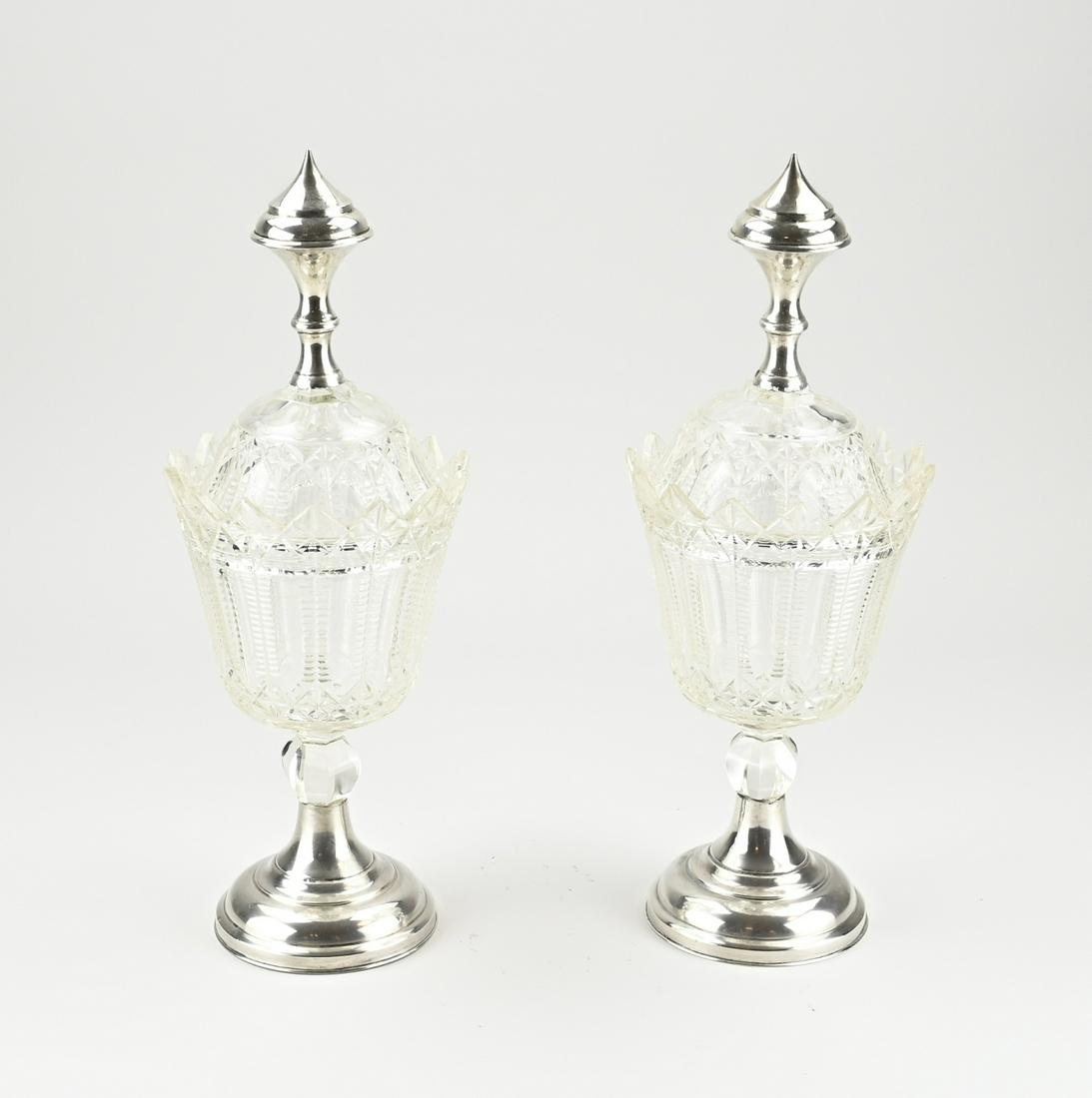 2 crystal candy coupes with silver: Two crystal candy cups with silver, 833/000. Beautifully cut candy sections placed on a silver round base and the lids are fitted with silver stoppers. Ã¸15x37cm. Some chips and the base is slightly