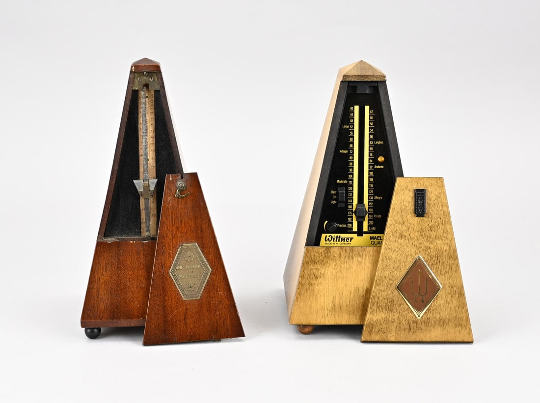2x Metronome in cabinet: Two old/antique metronomes for keeping time/tempo in music. 1x Antique mahogany, circa 1900. 1x Battery, second half 20th century. Dimensions: H 22 cm. In good condition.