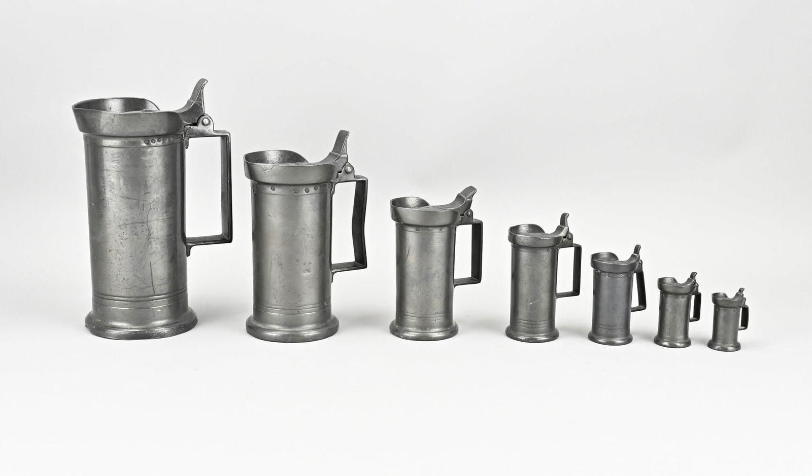 7-Piece Pewter Measuring Set: 7-piece antique tin measuring set. With bottom marks. Size: 7 - 22 cm. In good condition.