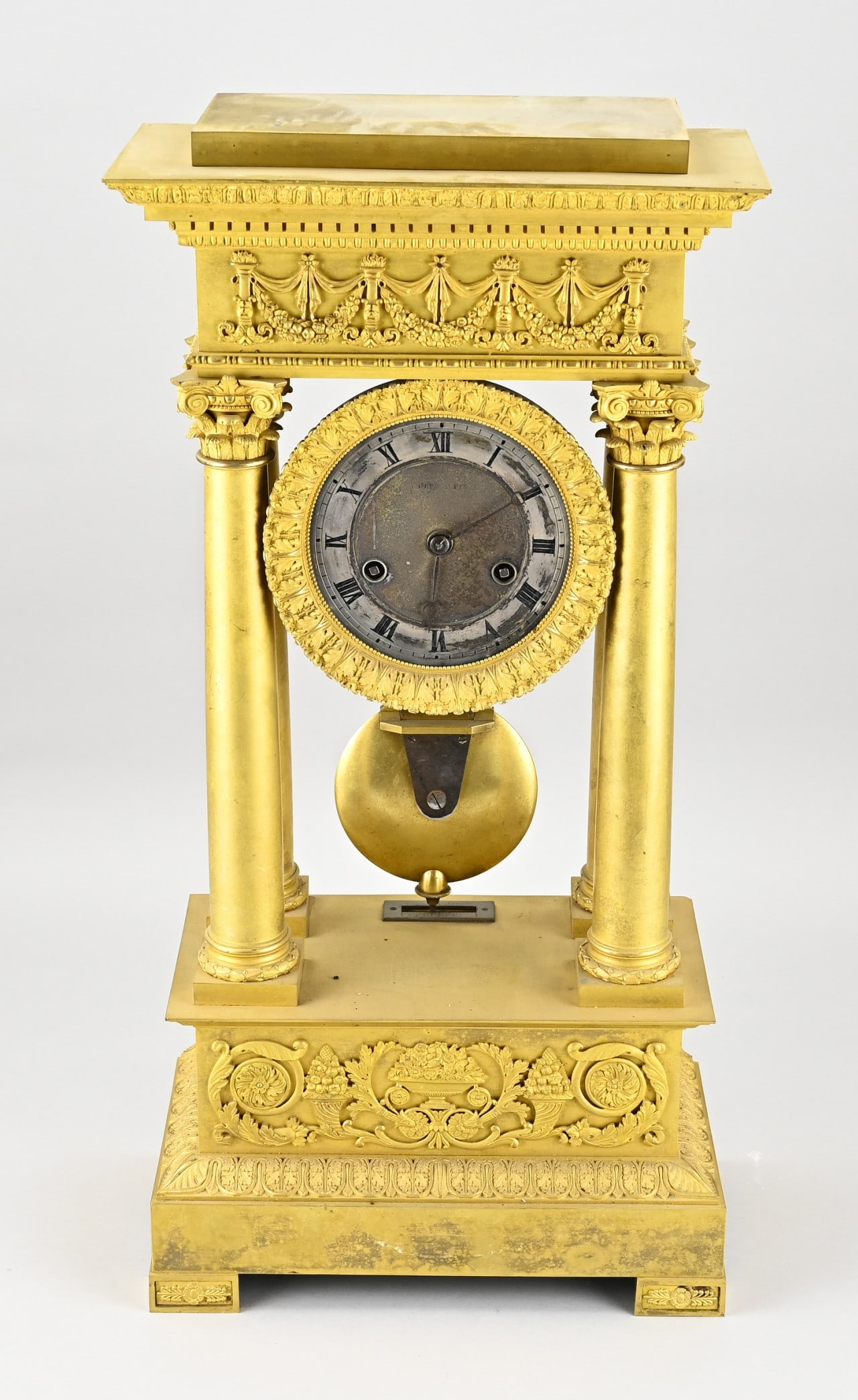 Fire-gilded pendulum clock: French fire-gilt bronze Empire mantel clock with Corinthian columns. Eight-day movement, half-hourly striking, spring pendulum. Size: 60 cm. Clock needs cleaning. In good condition.