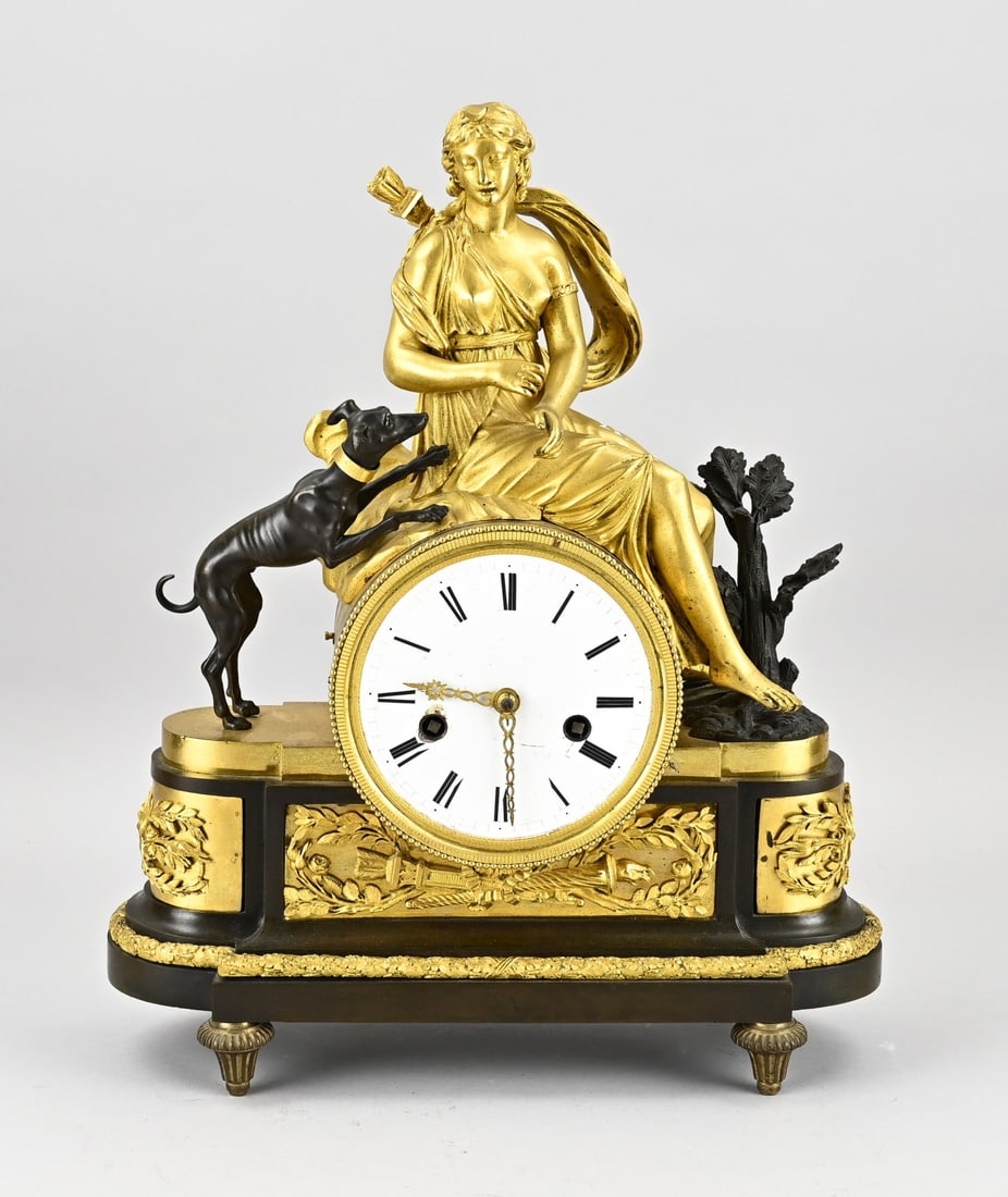 French clock, Deiana with hunting dog: Bronze, fire-gilt and burnished French Directore mantel clock with Deiana and hunting dog. Circa 1810. Eight-day movement, half-hourly striking, spring pendulum (adjusted). Dimensions: 43 x 35 x 14