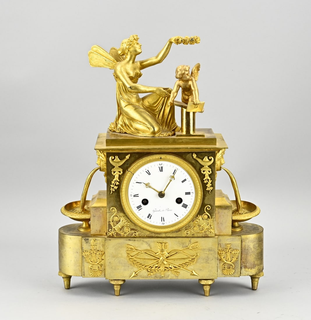 Fire-gilded empire pendulum: Antique fire-gilt bronze Directoire/Empire mantel clock. France. With wood nymph, angel, water spinners. Crack line at one leg (base right) + crack in lunette. Otherwise in good condition. Eight-day