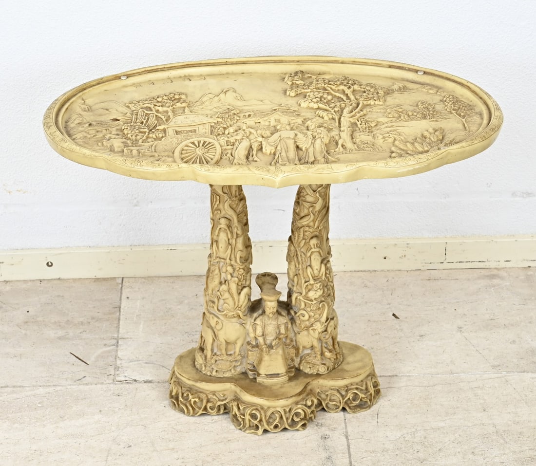 Chinese side table: Richly decorated Chinese side table. The top is decorated with a landscape and figures in a carriage. The foot is decorated as two carved tusks with two figures. All made entirely of plastic. Second
