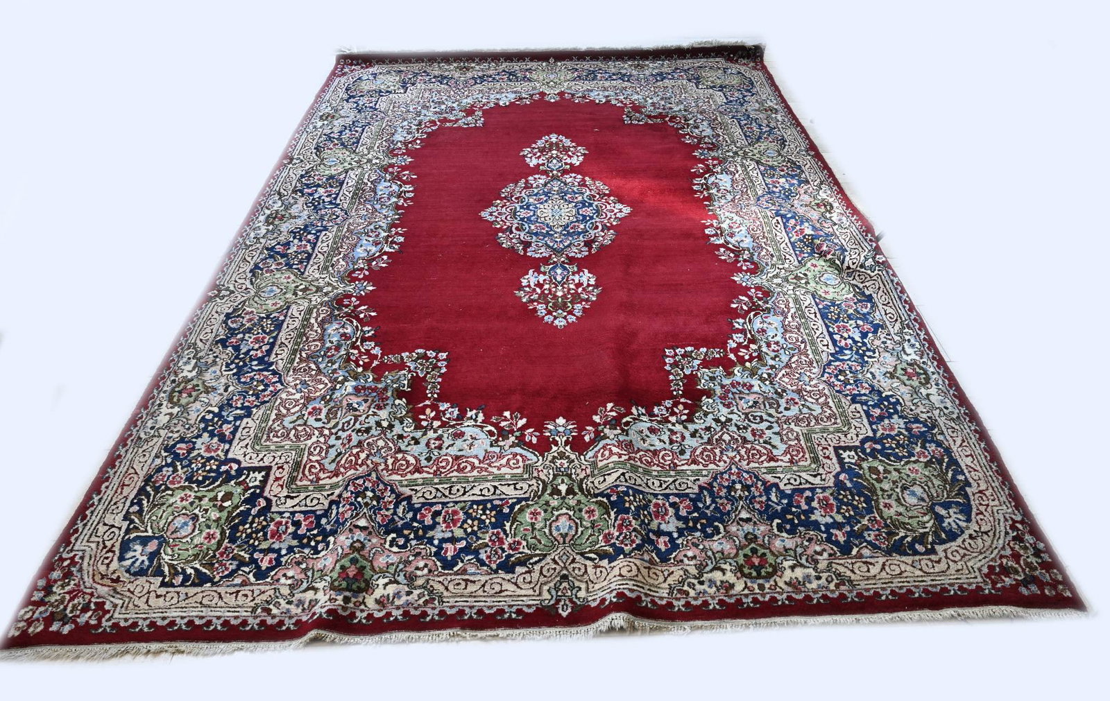 Persian Kirman carpet, 370 x 250 cm.: Hand-knotted Persian Kirman rug. Colour: mainly red, with a light blue floral border and a medallion in the middle. Size: 370 x 250 cm. In good condition.