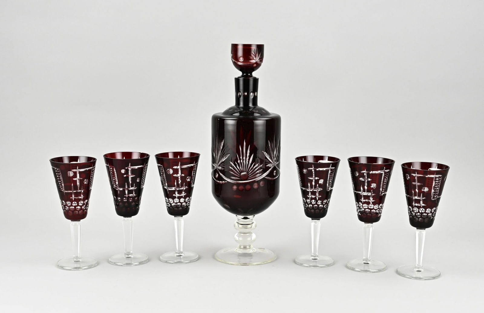 Bohemian crystal set: 7-piece Bohemian crystal liqueur set. Ruby red. Facet cut. Size: 17 - 35 cm. In good condition.