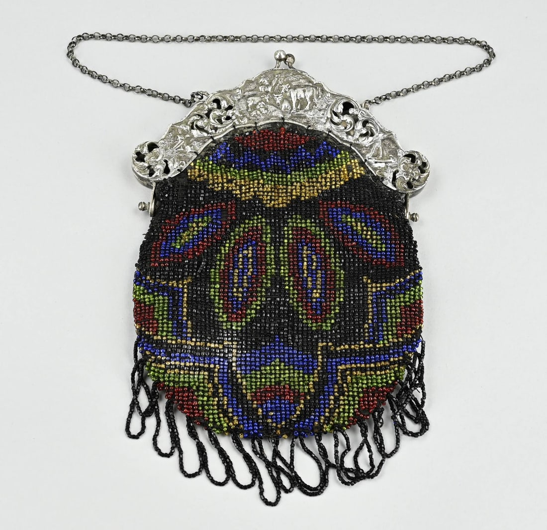 Silver purse: Bag with silver clasp, 833/000, round contoured model, partly openwork. Decorated with animals, figures, mill and sailboat. Provided with a silver chain. The bag is provided with a beaded purse. 16x23