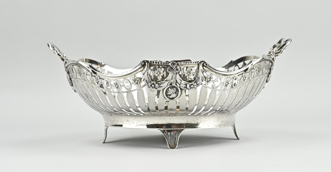 Silver bread basket: Silver bread basket, 833/000, oval sawn model with bars and flower and oval decoration. With garlands and medallion. Placed on 4 legs and provided with 2 handles in the shape of double bows. MT.: WA