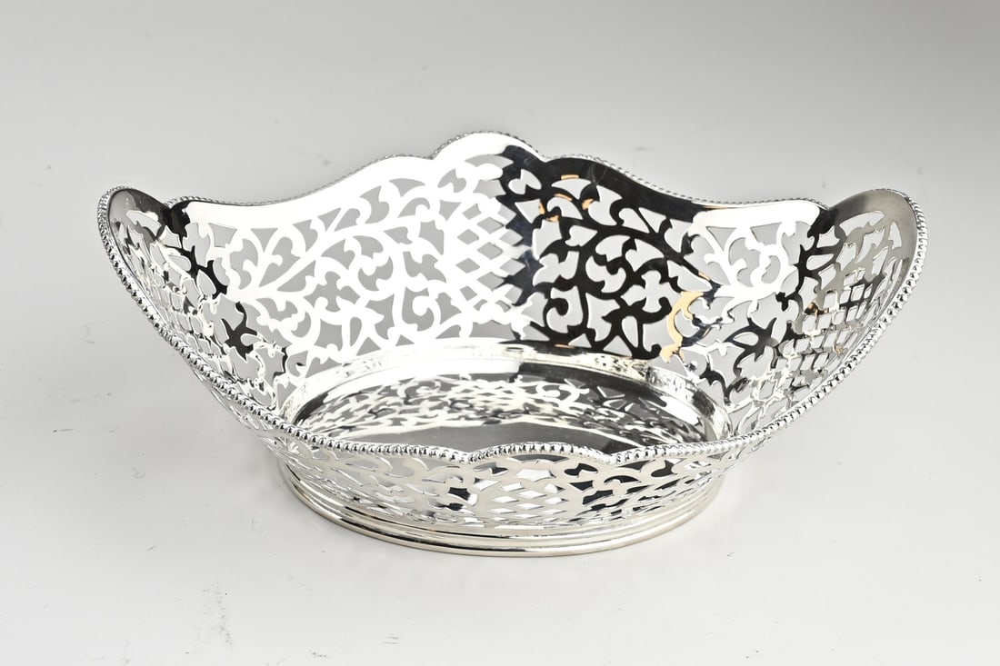 Silver candy basket with saw work: Silver bonbon basket, 835/000, oval contoured model with a sawn floral decoration with pearl edge. Placed on an oval ring with filet edge. 18x14.5x6.5cm. approx. 155 grams. Provided with an engraving