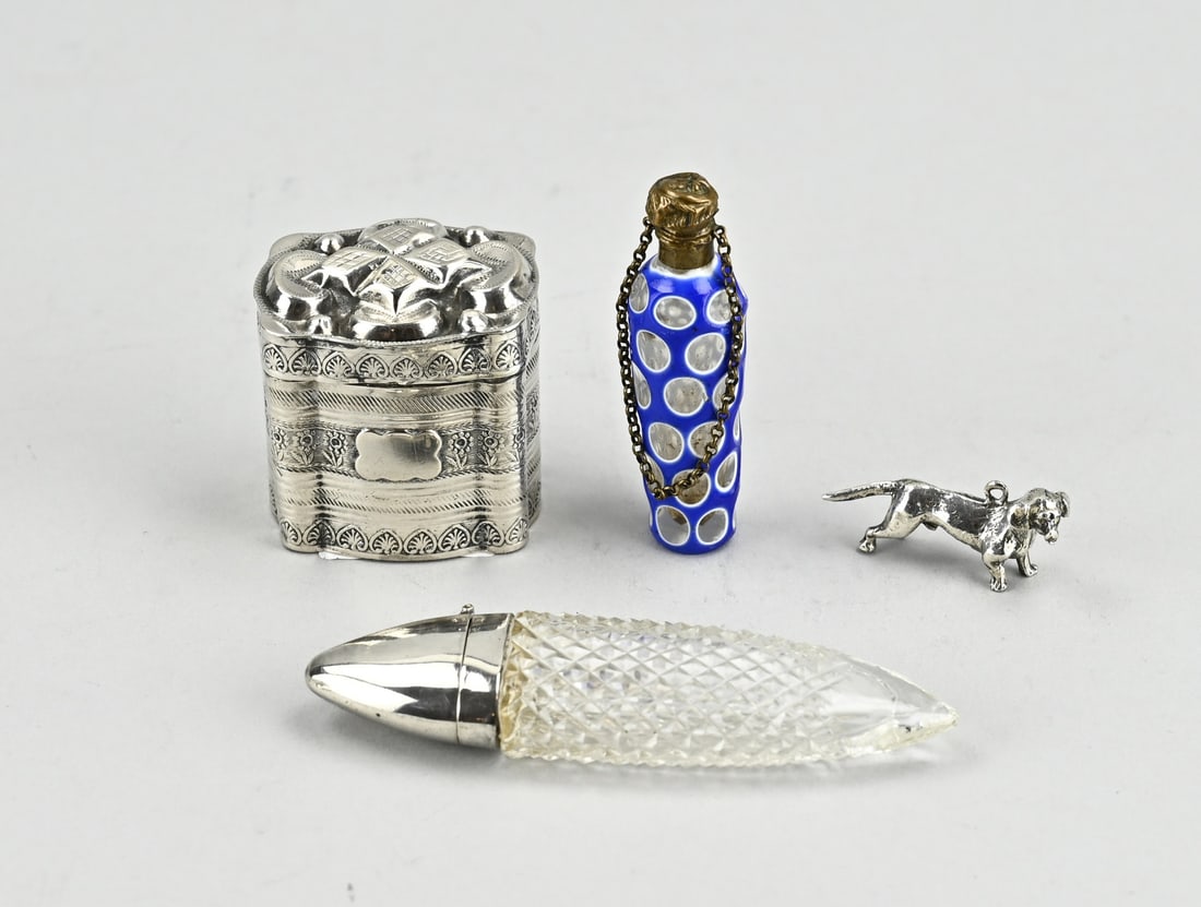 4 Parts with silver: Lot with 4 parts, partly silver, a silver snuff box, 833/000, oval contoured model with strap work. The lid is provided with a chased work. 4x3x3.7cm. MT.: Fa. Gebr. Reitsma, Heerenveen, 1859-1892.,