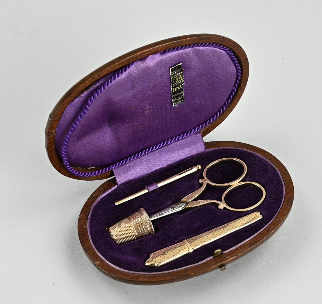 Golden sewing set in mahogany cassette: Yellow gold sewing kit, 585/000, in an oval mahogany wooden case. Gold needle, needle case, thimble and scissors with gold handles, provided with a pointillist decoration. 13x8cm. Weight without
