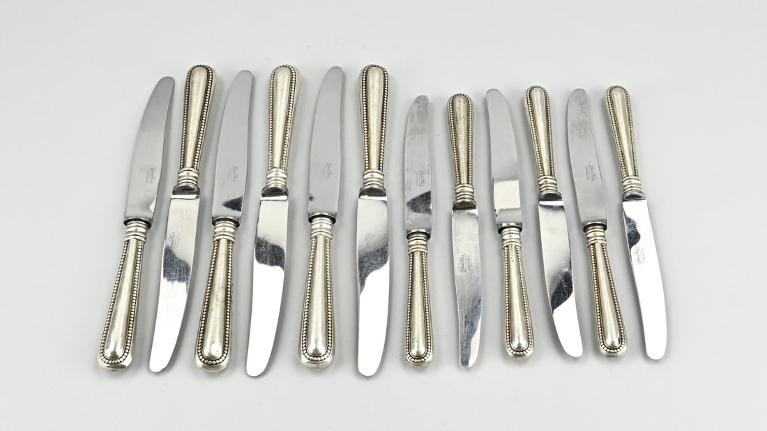 12 Knives with silver: Twelve knives with silver handle, 835/000, decorated with a pearl rim. MT.: Gebr. Huisman, Schoonhoven. jl.:P:1975. Minimal dents. 21-24cm. In good condition.