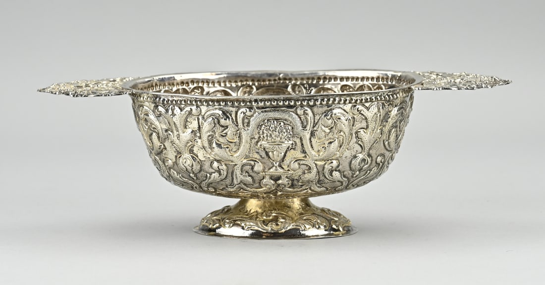 Frisian silver brandy bowl: Beautiful silver brandy bowl, Frisian 18th, with embossed images of curls and floral decoration. Provided with flat ears with figures and flower basket. Restoration along the edge. 25x11x8cm. Total