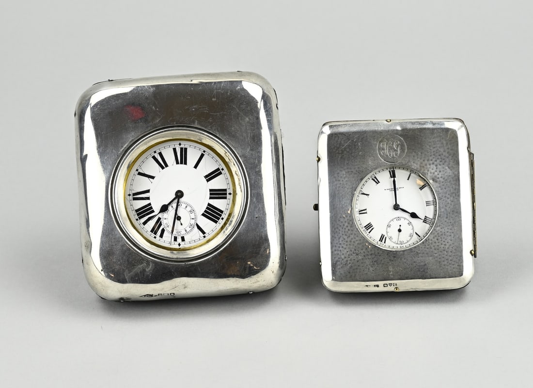2 Watches in silver holder: Two pocket watches placed in a standing holder with silver front. 925/000. Small model with an engraving: HG. English. 10x11cm, 8x8.5cm. Somewhat dented. In reasonably good condition.