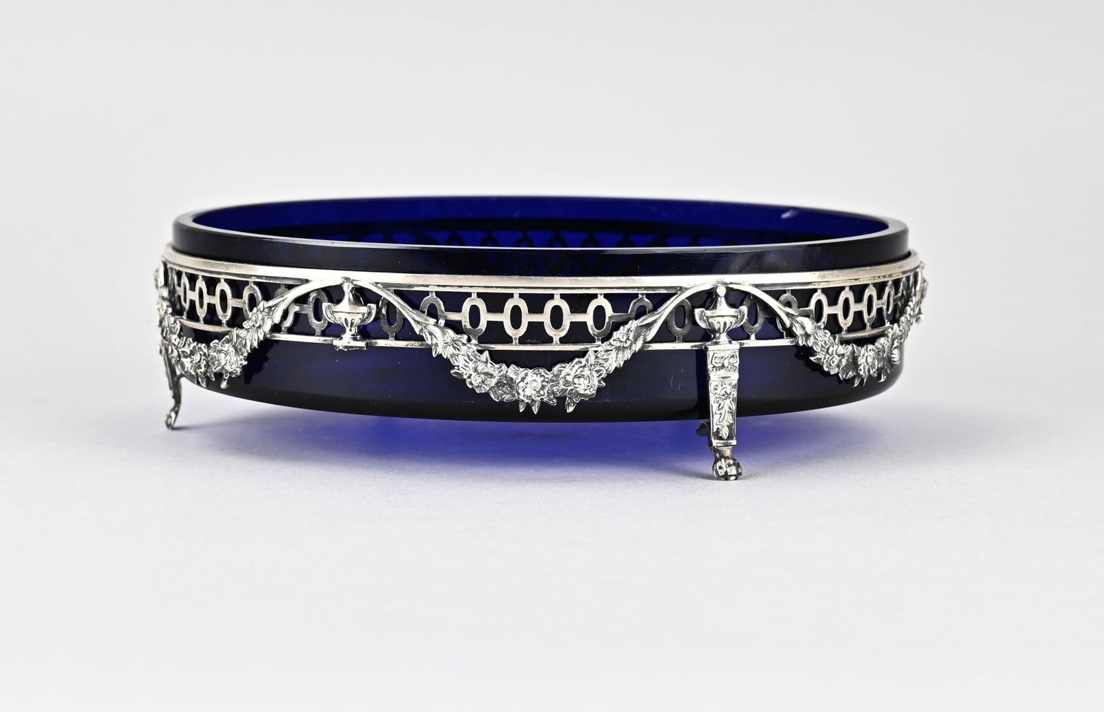 Silver jardiniere/blue glass: Silver jardinaire, 833/000, with blue glass. Oval openwork jardinaire placed on claw feet, 2 are missing, with floral decoration and vases, garlands. Total approx. 559 grams. 20x14x6cm. Some