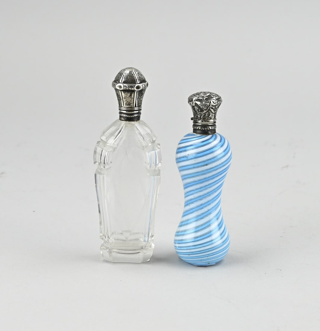 2 Fragrance bottles with silver: Two perfume bottles with silver, one bottle with Venetian glass, spiral-shaped with white and blue. Provided with a silver collar and stopper with floral decoration, and inner stopper. 10 cm. And a
