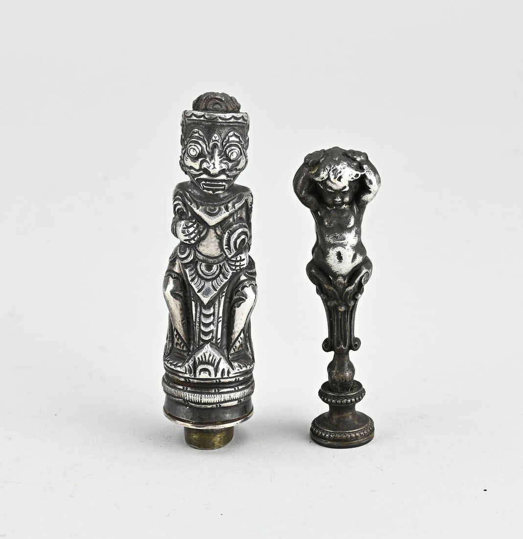 2 Wax seal stamps with silver: Two sealing seals, a metal seal with a handle in the shape of a putti, 8 cm., and a sealing seal, silver 800/000, with djokja figure. 9.5 cm. Provided with a monogram in the seal. approx. 84 grams, fi