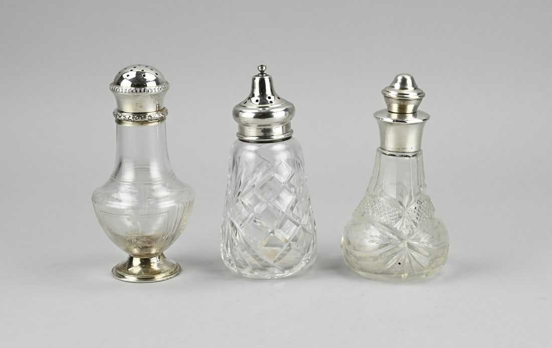 Lot of crystal with silverware (3x): Three pieces of crystal with silver. A flacon with etching, set on a silver round base and with a silver round sprinkle cap decorated with a floral border. 950/000, France. ø7.5x15cm. A conical cut