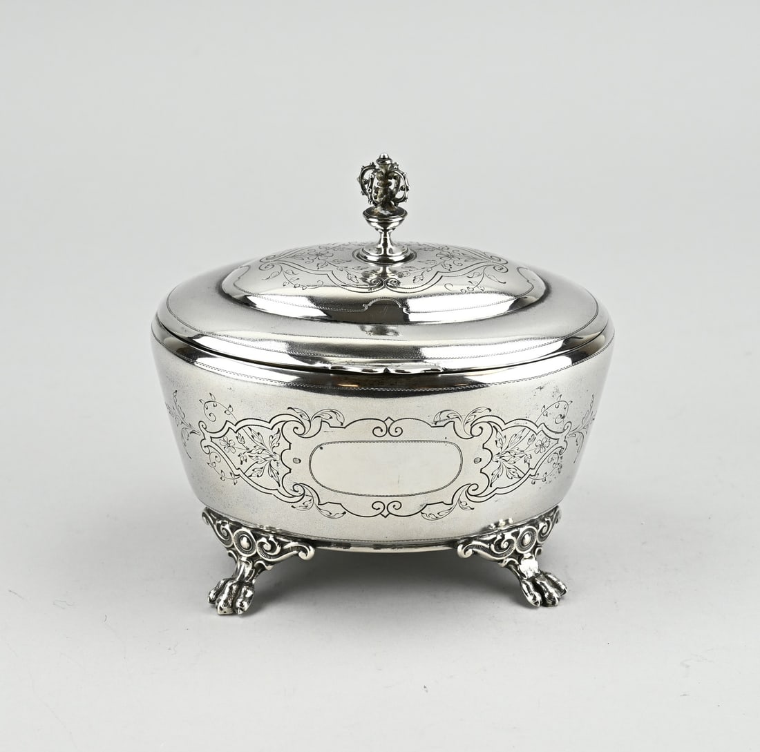 Silver cookie box: Silver box, 800/000, oval model placed on 4 claw feet. The box is decorated with engraving and the hinged lid is provided with engraving and a knob in the shape of a crown. approx. 297 grams.