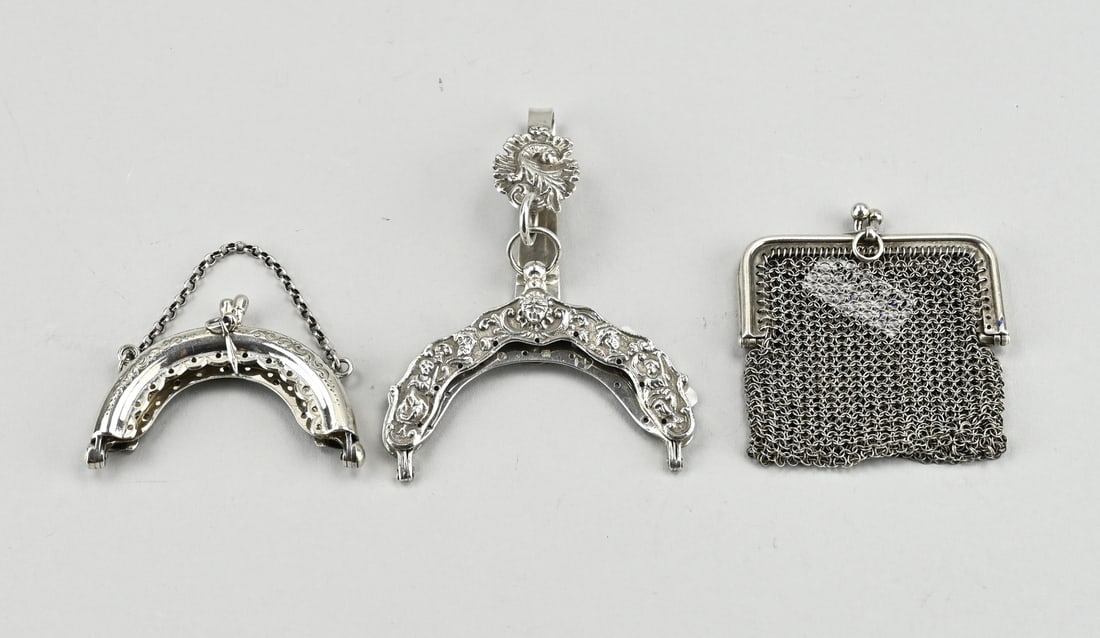 3 Silver brackets: Lot with 3 silver clasps, including a chain mail purse with rectangular clasp, 6 cm., a semi-circular model with engraving and a chain, 6.5 cm. and a contoured clasp with a representation of figures.