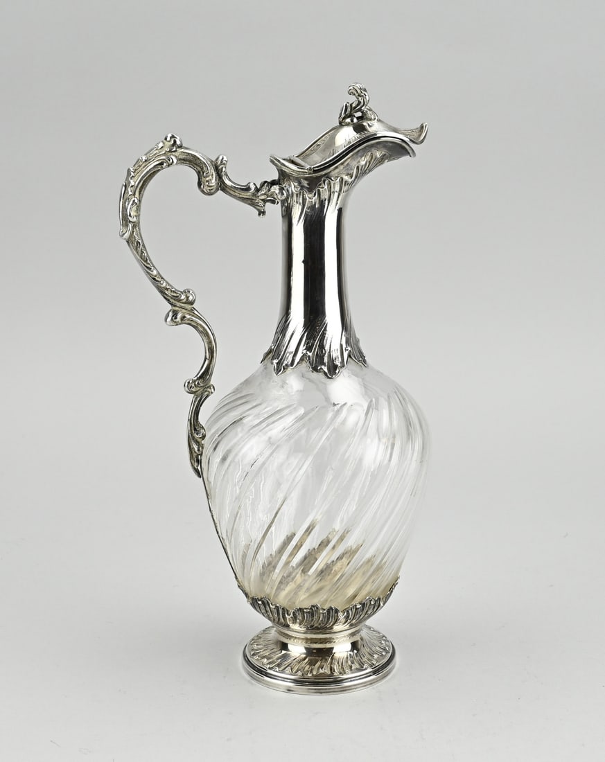 Carafe with silverware: Crystal decanter with silver mount, 950/000, decanter with a diagonally cut pattern, placed on a round silver base with acanthus leaves and a silver mount with a pouring spout with valve and handle