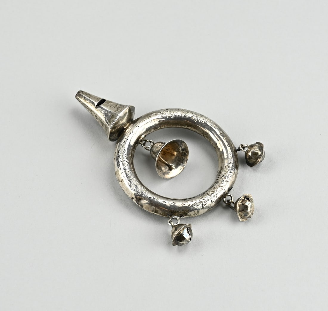 Silver rattle: Silver rattle, 833/000, in the shape of a ring decorated with engraving. The rattle is decorated with 4 bells and a whistle. 11.5x6.5cm. Some small dents in the edge. MT.: unclear. approx. 31 grams.