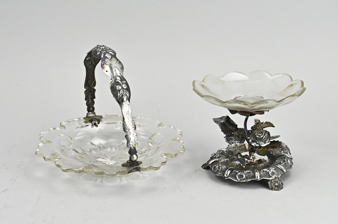 2 Crystal tazzas on silver base: Two crystal tazzas with silver. A crystal bowl with contoured edge provided with a silver bracket, 835/000, decorated with floral embossed decoration. ø18x15cm. And a bowl placed on a silver foot