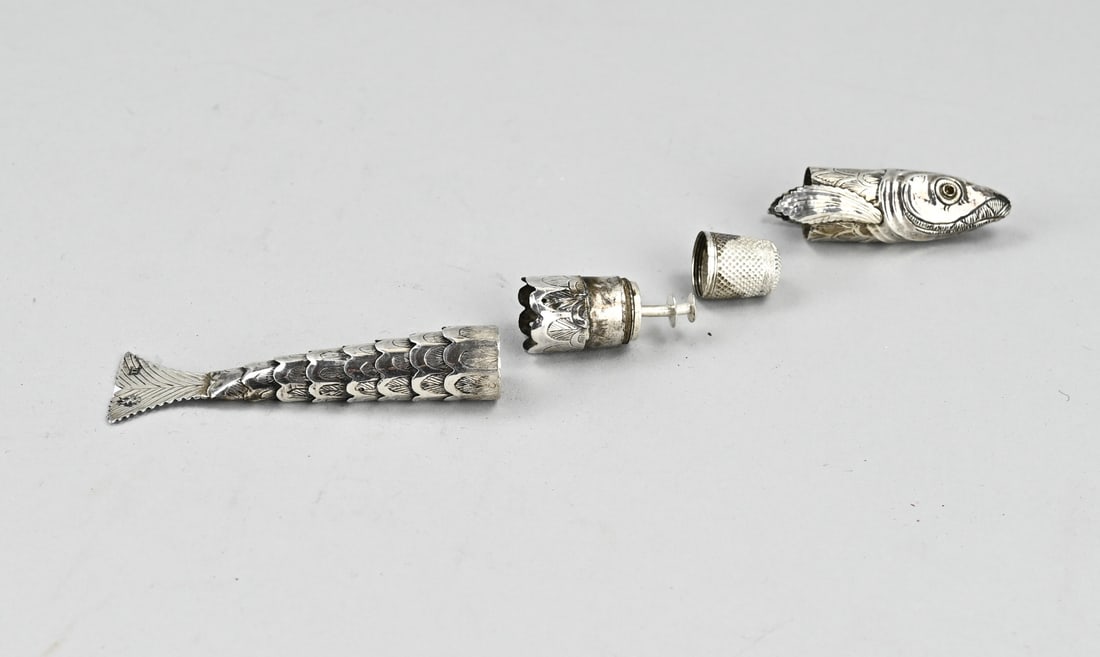 Silver sewing kit: Antique silver sewing kit, in the shape of a fish with a flexible body. Equipped with a thimble, a bobbin and a needle case. One eye of the fish is provided with a pink stone. 13.5 cm. approx. 31