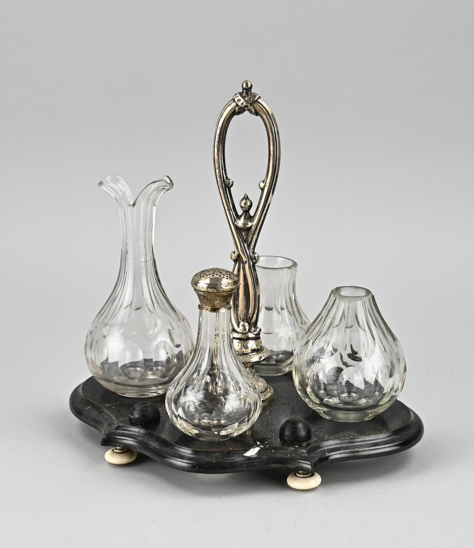 Oxygen set with silverware: Crystal table set with silver, 833/000. Contoured wooden base with 4 crystal carafes, vases and a shaker with silver sprinkle cap. The set has a curled silver handle. 25x18x24 cm. Some caps are